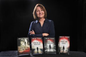 Author Joni M Fisher is shown with her Compass Crimes series books.